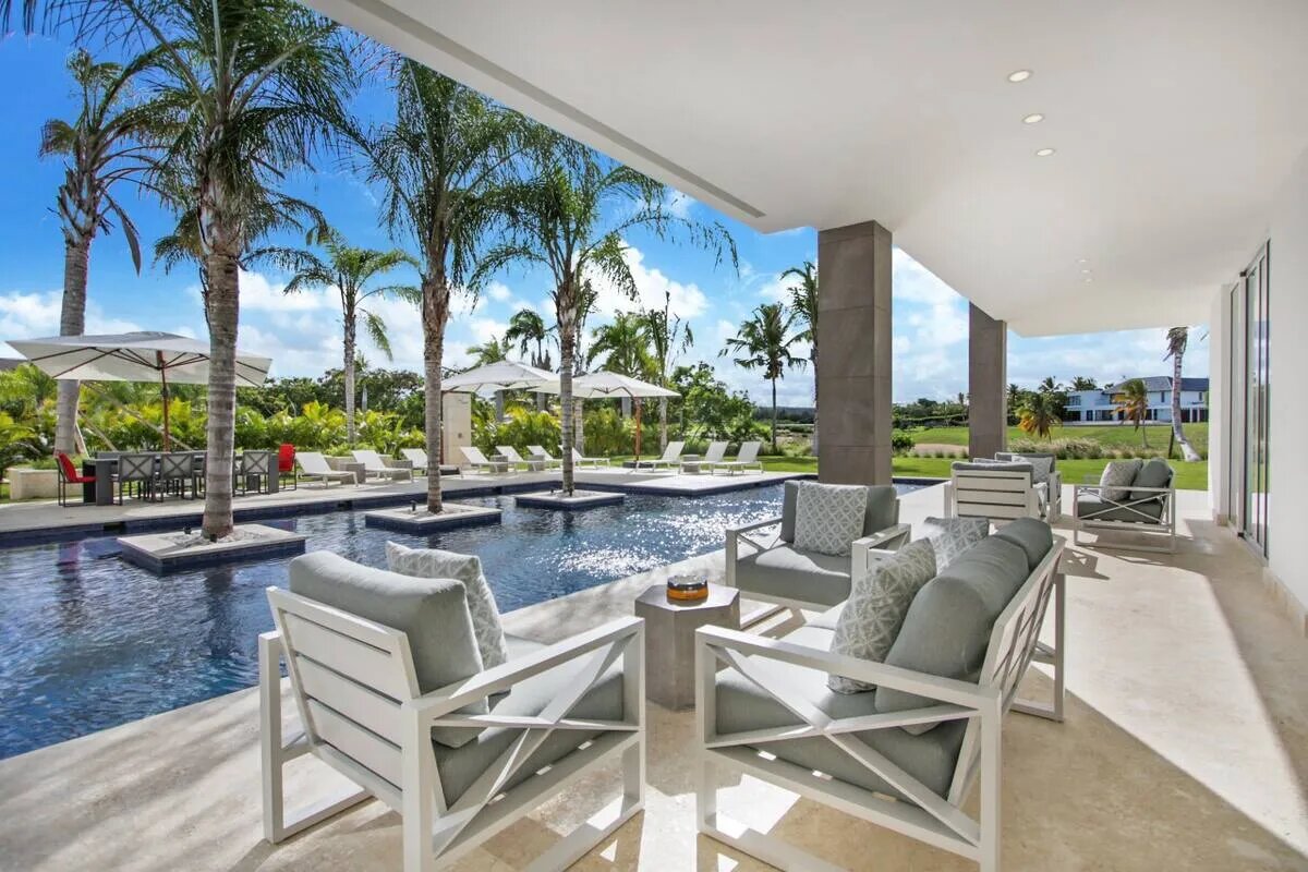 Hay una terraza cubierta junto a la piscina cerca de la villa